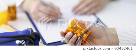 Patient holding jar of medicines in his hands against background of doctor closeup Patient holding jar of medicines in his hands against background of doctor closeup 93492461