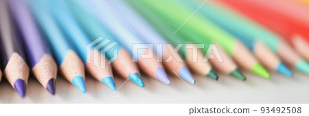 Many sharp multicolored pencils lying over colors of rainbow closeup background 93492508