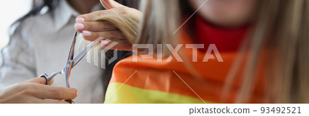 Woman hairdresser cutting ends of client hair with scissors closeup Woman hairdresser cutting ends of client hair with scissors closeup 93492521