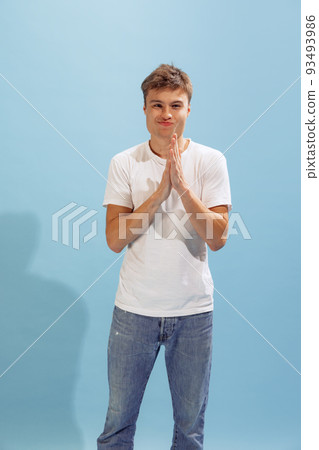 Portrait of young man in casual clothes rubbing hands, posing isolated over blue studio background. In excitement Portrait of young man in casual clothes rubbing hands, posing isolated over blue studio background. In excitement 93493986