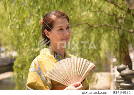 A senior woman wearing a yukata and strolling around the hot spring town A senior woman wearing a yukata and strolling around the hot spring town 93494925