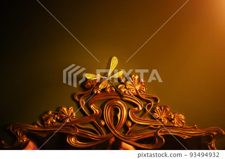 Fragment of a bronze vintage mirror frame. Decorative dragonfly on a mirror. A fairy tale mirror frame. Blurred image 93494932