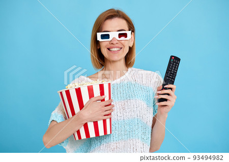 woman watching movie film, holding bucket of popcorn woman watching movie film, holding bucket of popcorn 93494982