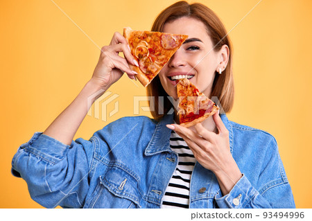 woman covering her eyes with a slice of fresh pizza 93494996