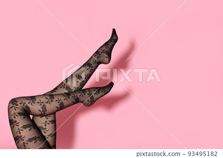 female legs in black tights on pink background. 93495182