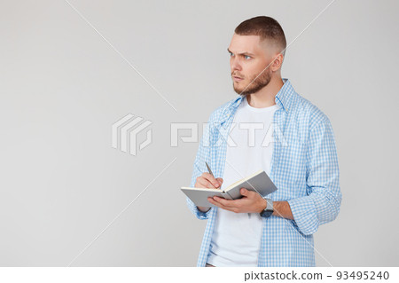 handsome man in blue shirt writing note in notebook 93495240