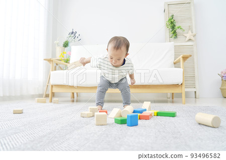 Baby playing with building blocks alone in the living room 93496582