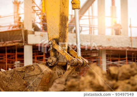 Bucket of backhoe. Digger parked at construction site. Bulldozer on blur building under construction and worker. Earth moving machine. Dirt bucket of digger. Earth moving machine. Excavation vehicle. 93497549
