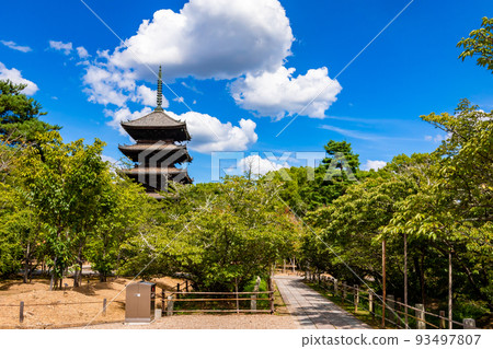 A five-storied pagoda in the depths of the trees covered with green leaves and a clear blue sky seen at Ninna-ji Temple in Kyoto in midsummer A five-storied pagoda in the depths of the trees covered with green leaves and a clear blue sky seen at Ninna-ji Temple in Kyoto in midsummer 93497807