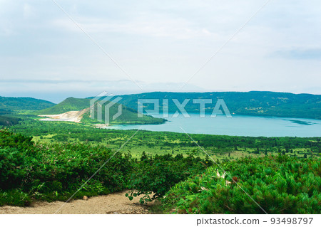 natural landscape of Kunashir island, view of the Golovnin volcano caldera with hot lakes and a path through the thickets of sasa and dwarf pines on a foreground natural landscape of Kunashir island, view of the Golovnin volcano caldera with hot lakes and a path through the thickets of sasa and dwarf pines on a foreground 93498797