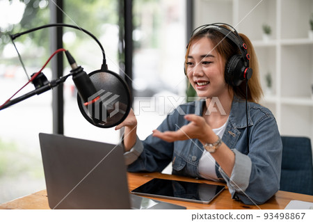 Young asian woman makes a podcast audio recording at home. 93498867