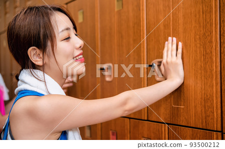 Young woman worried at locker in gym 93500212