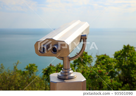 Coin Operated Binocular viewer or touristic telescope, trees and sea, panoramic view. Closeup. 93501090