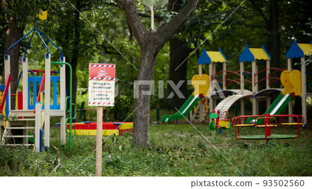 Horenka, Ukraine - August 25, 2022: The consequences of russian invasion in Kyiv region near Gostomel. Playground and sign. Words on the sign: Beware Mines 93502560