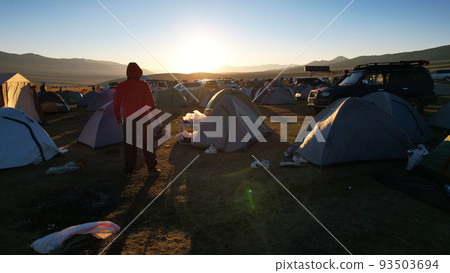 A guy at dawn looks at a camp covered in garbage 93503694