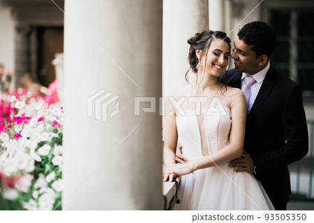 Beautiful bride and groom embracing and kissing on their wedding day outdoors 93505350