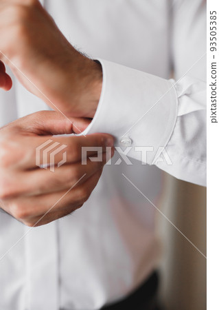 Grooms morning preparation. Handsome man getting dressed and preparing for the wedding Grooms morning preparation. Handsome man getting dressed and preparing for the wedding 93505385