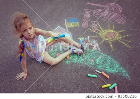 Child from Ukraine draws with chalk. 93506216