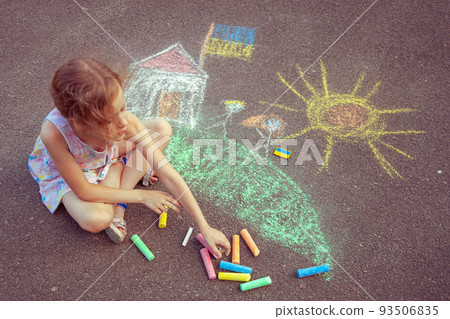 Child from Ukraine draws with chalk. 93506835