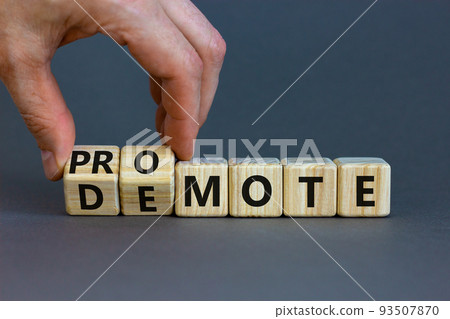 Promote or demote symbol. Businessman turns cubes and changes the word 'demote' to 'promote'. Beautiful grey background. Business, demote or promote concept. Copy space. Promote or demote symbol. Businessman turns cubes and changes the word 'demote' to 'promote'. Beautiful grey background. Business, demote or promote concept. Copy space. 93507870