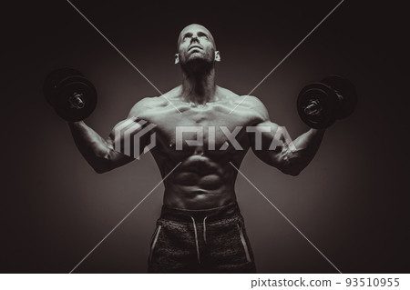 Strong young man bodybuilder performing exercise for biceps with heavy weights in both hands. Concept Gym Life Style.Toned Image. 93510955
