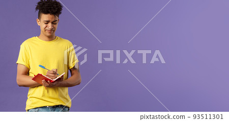 Portrait of unamused, displeased and bothered young man having troubles with homework, smirk and grimacing, trying solve math equation, writing down in notebook, fill-in schedule 93511301