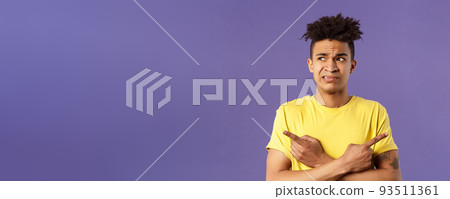Close-up portrait of insecure, indecisive young hispanic man cant make up his mind, deciding between two variants, dont know what choose, need help with decision, pointing fingers left and right 93511361