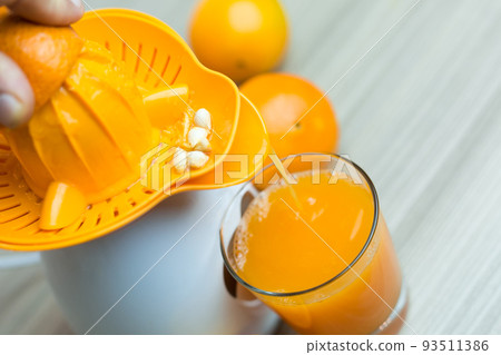 Awesome woman in the kitchen squeezing fresh orange juice with an electric juicer. 93511386