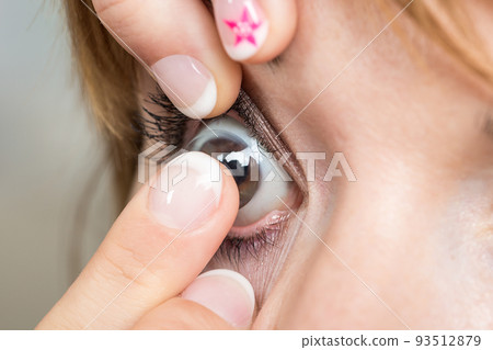Young woman putting contact lens in her eye Young woman putting contact lens in her eye 93512879