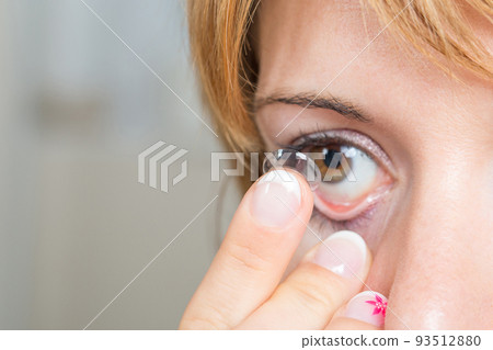 Young woman putting contact lens in her eye Young woman putting contact lens in her eye 93512880