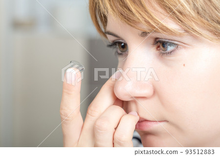 Young woman putting contact lens in her eye Young woman putting contact lens in her eye 93512883