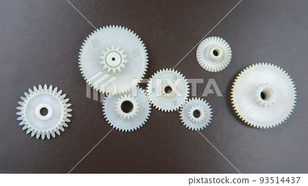 white plastic gears on a dark background. connection mechanism details. subject of movement 93514437