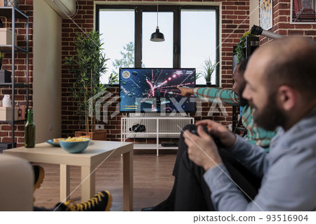 Diverse group of men playing online video games on tv console, gaming competition with controller. Friends having fun with game play on television, celebrating friendship event. Diverse group of men playing online video games on tv console, gaming competition with controller. Friends having fun with game play on television, celebrating friendship event. 93516904
