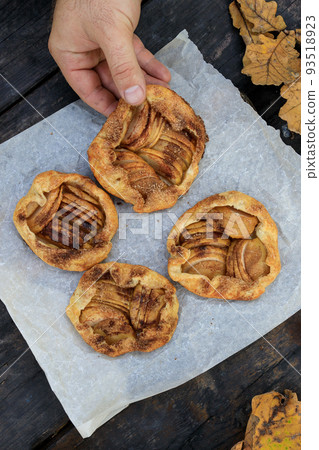 holds in hand a rustic traditional french biscuit cake with apples in autumn style, top view holds in hand a rustic traditional french biscuit cake with apples in autumn style, top view 93518923