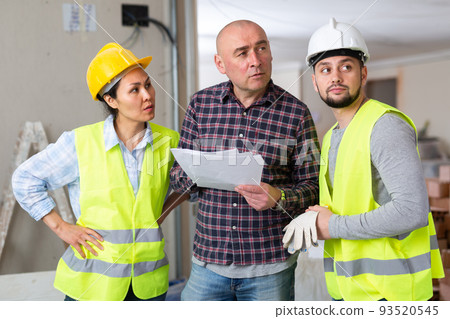 Homeowner discussing home renovation work plan with builders 93520545