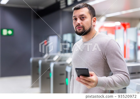 Guy traveler standing on subway station with phone in hands Guy traveler standing on subway station with phone in hands 93520972