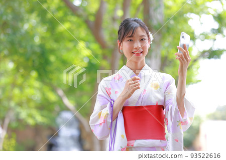 一個穿著浴衣的女人拿著智能手機微笑著 1 一個穿著浴衣的女人拿著智能手機微笑著 1 93522616