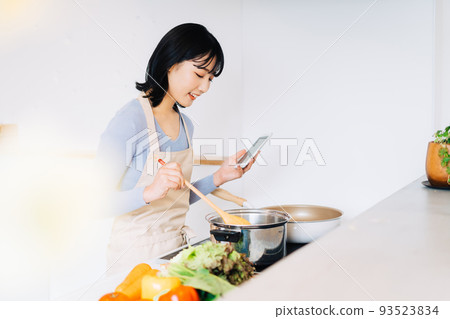 烹調的婦女，當觀看智能手機時 93523834