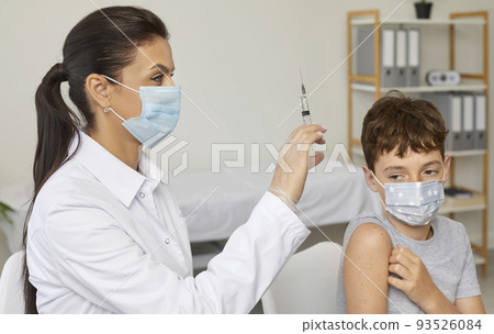 Doctor or nurse with a syringe is going to give a vaccine to a little school boy Doctor or nurse with a syringe is going to give a vaccine to a little school boy 93526084