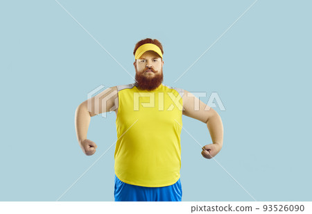 Funny serious fat man showing muscles after sports workout on light blue background. 93526090