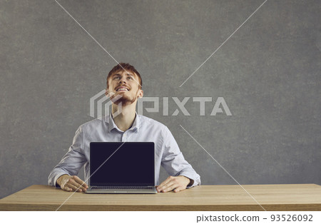European cheerful man shows a laptop with a black screen on the table 93526092