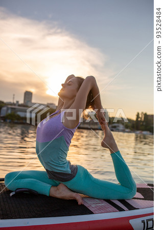 Young beautiful woman meditating in a sea at SUP paddleboarding. Healthy lifestyle. 93528484