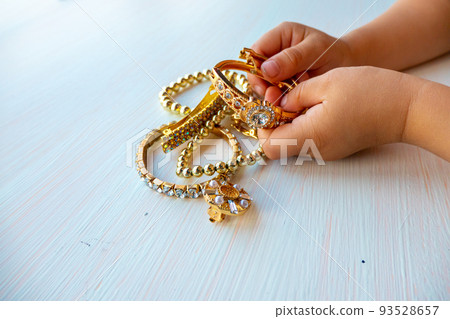childrens hands play with gold jewelry and bijouterie, on white background. concept of womens happines 93528657
