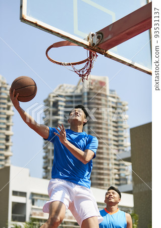 young asian adult players playing basketball on outdoor court young asian adult players playing basketball on outdoor court 93531137