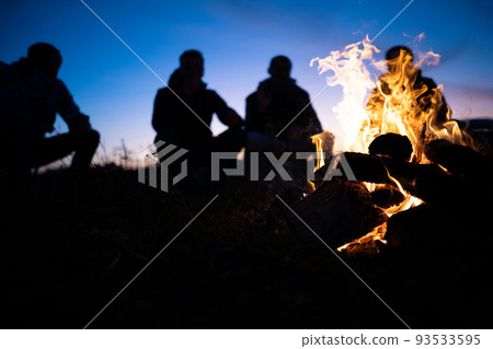 a group of friends gathered around the fire at night a group of friends gathered around the fire at night 93533595