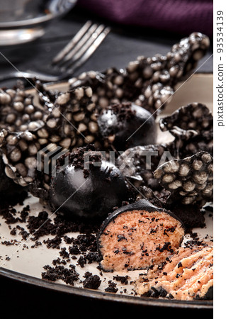 Appetizer with salmon pate, ink cuttlefish, crackers served on white tray over black wooden background. Close-up 93534139