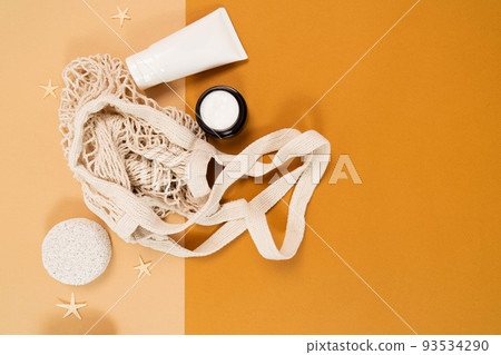 A layout for your natural eco cosmetics product and, copy space for your advertising. Cream, green leaf, a tube of cream, a mesh bag on a light beige background. A layout for your natural eco cosmetics product and, copy space for your advertising. Cream, green leaf, a tube of cream, a mesh bag on a light beige background. 93534290