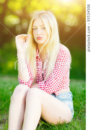Beautiful young blonde woman with checked shirt relaxing in the park Beautiful young blonde woman with checked shirt relaxing in the park 93534506