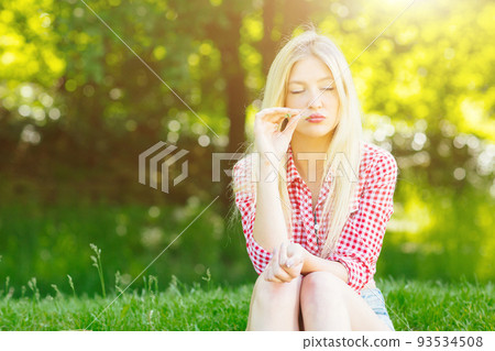 Beautiful young blonde woman with checked shirt relaxing in the park Beautiful young blonde woman with checked shirt relaxing in the park 93534508