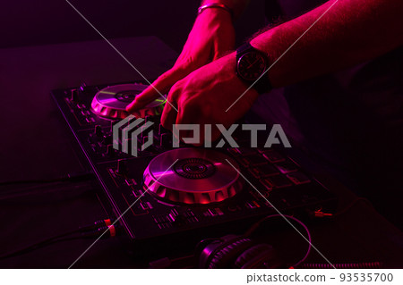 Dj mixing on turntables with color light effects. Soft focus on hand. Close-up. Dj mixing on turntables with color light effects. Soft focus on hand. Close-up. 93535700